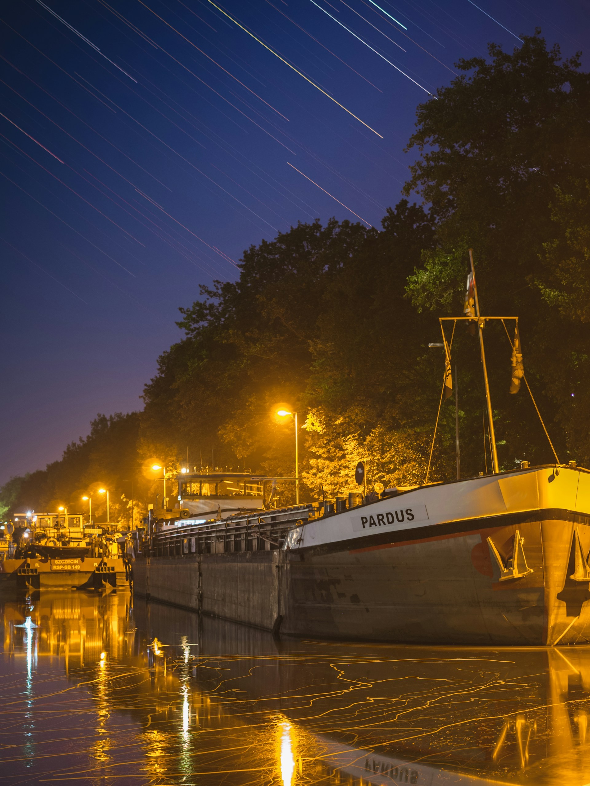 Long exposure of a boat in a canal at night. The water and the stars draw lines.