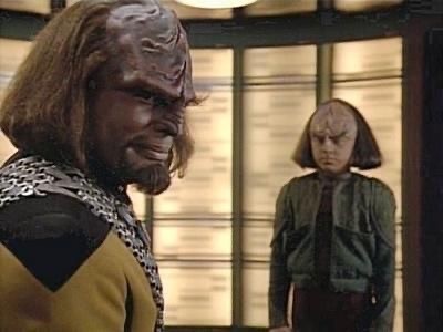 Two characters with distinctive ridged foreheads from the Star Trek series, likely Klingons, standing in a room with futuristic decor.