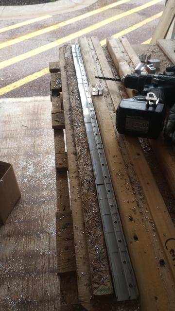 A line of clips held between two boards for easier drilling.