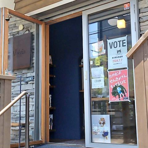 アルビジア鎌倉長谷店の入口の写真。投票を呼びかけるポスター、選挙割の宣伝、パレスチナに連帯するパッチが貼ってあるガラス戸。