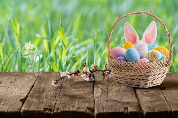 An Easter basket on a wooden platform in front of grass