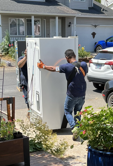 Two guys carrying an old refrigerator 