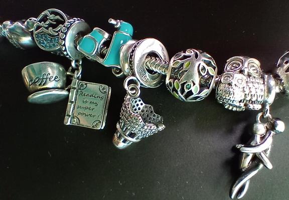 Part of my charm bracelet with a brand new charm - badminton shuttlecock. Other charms you can see are: a sloth, a sea with seagulls above, coffee cup with a book, a torquise vespa, a tree, mother owl wit a small owl, a hugging couple.