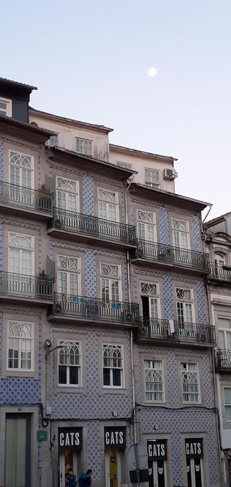 Building in Porto full of windows and traditional tiles seen on full moon morning