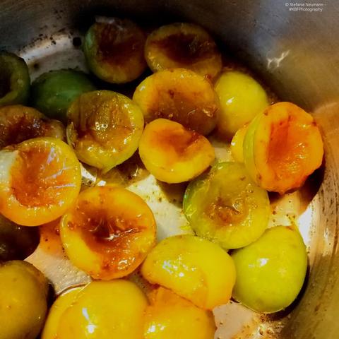 Halved and pitted greengages in a pot, mixed with a bit of brown sugar to start plum butter.