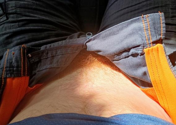 Photo shot POV from head pointing down at crotch, shirt raised showing belly, fly unbuttoned with no underwear revealing red pubic hair but no genitals