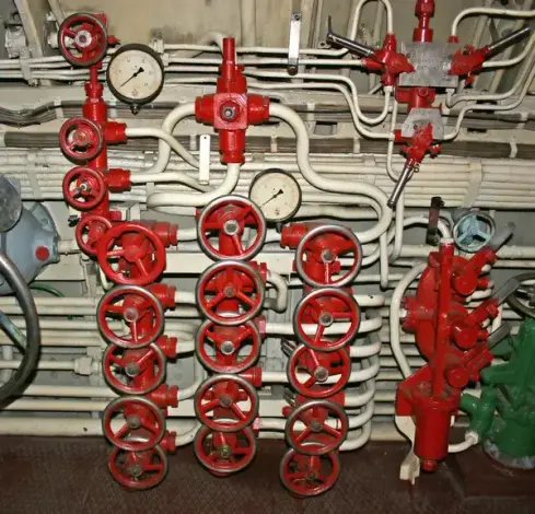Many different sized white pipes each with several red valves on each