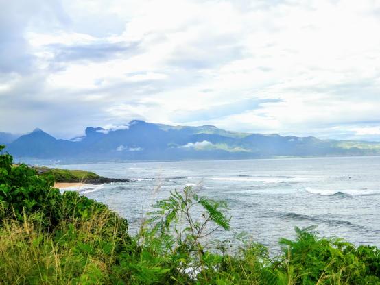 Ein bewölkter Tag an der Nordküste entlang der berühmten Straße nach Hana. Der Blick geht fast genau nach Westen über die Bucht zum West Maui Nature Reserve, Wolken bedecken den Gipfel.