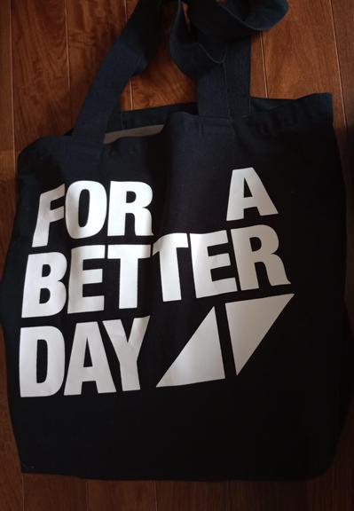 FOR A BETTER DAYの文字とアヴィーチーロゴのついた黒い布バッグ。