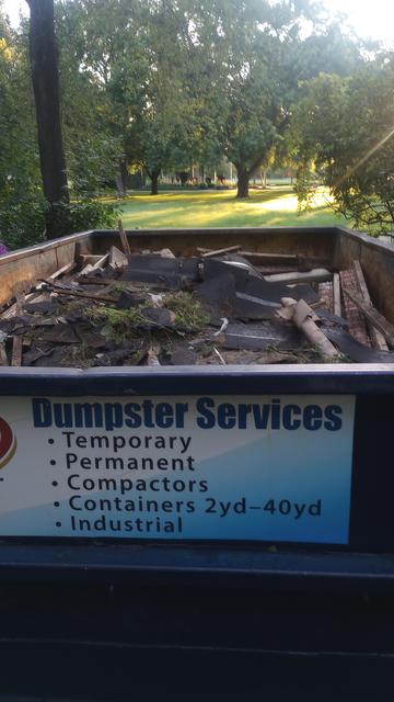 A 10 yard dumpster in the foreground. A sunset in the park beyond makes for a picture perfect evening. Just me and my trash.