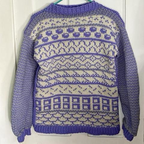 A periwinkle and cream knitted sweater with various colorwork patterns