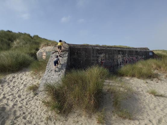 Two kids climbing on a blockhaus on the sand