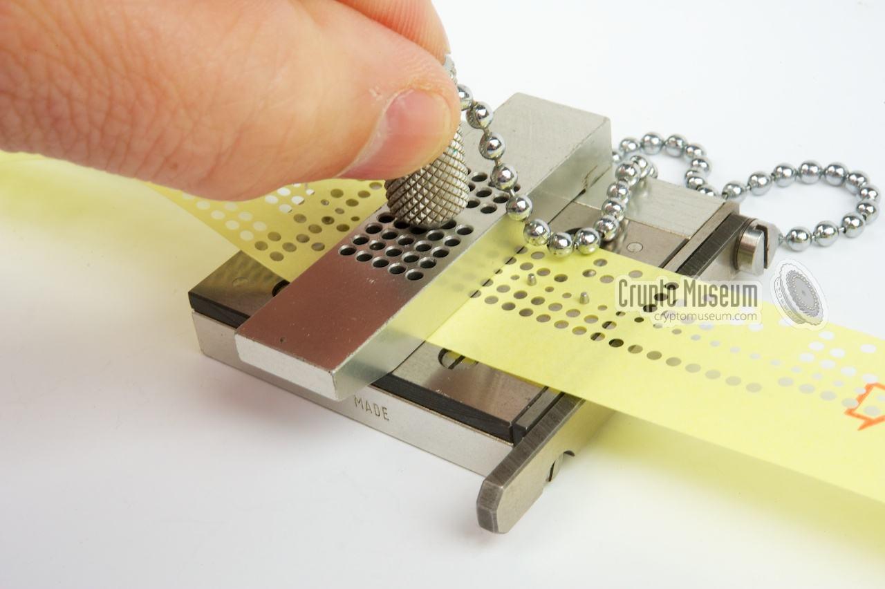 Using a hand punch on paper telex/teletype program paper roll 