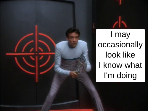 Panel 1 of a 2 part comic. Julian Bashir wears a light colored jumpsuit. The top panel of the jumpsuit is white. There's a teal stripe at the center of his chest. Everything below that level is grey. He stands in a futuristic black set with red target symbols painted on the walls. He holds a futuristic paddle or racket in his hands and he stands in position to deal with a ball coming his way.

The text says 