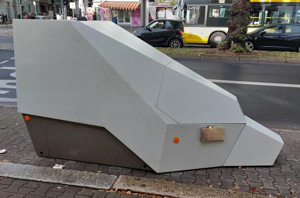 Ein Metall/Plastik Gehäuse in weiß/hellem grau, das wie ein stilisierter Eisberg aussieht. Unten sind Katzenaugen angebracht.