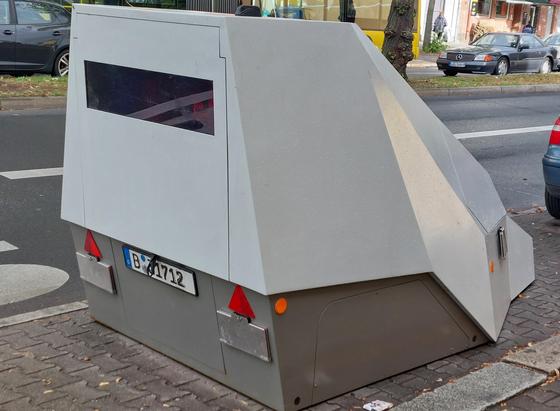 Das Eisberförmige Gebilde auf der Strasse. Auf der Rückseite ein ca 30cm hohes Fenster, ins Innere kann man nicht blicken. Das Gebilde ohne Räder hat ein Berliner Kennzeichen. 