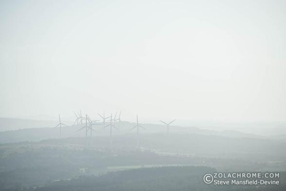 Landscape photograph of distant wind turbines on a bright but hazy day.