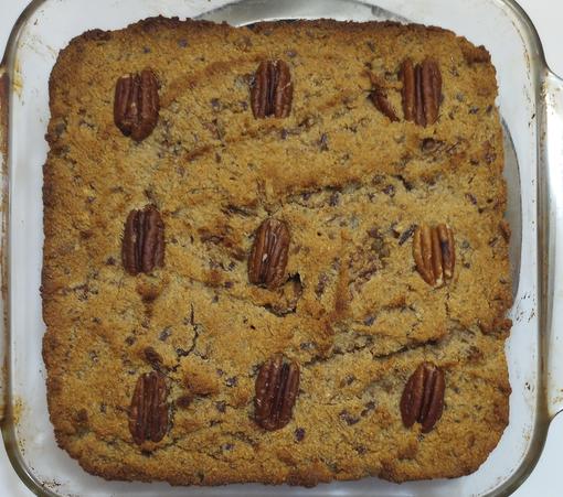 A square glass dish containing a cake decorated with pecan halves. 