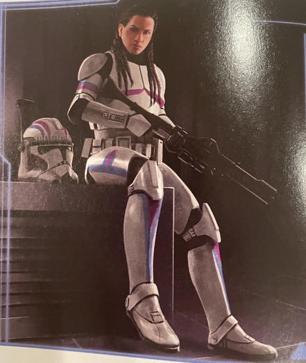 Image features a female Clone Trooper, , armored, sitting with a weapon. The character has long, braided hair and is alongside a helmet. The setting appears dark, emphasizing the character's presence.