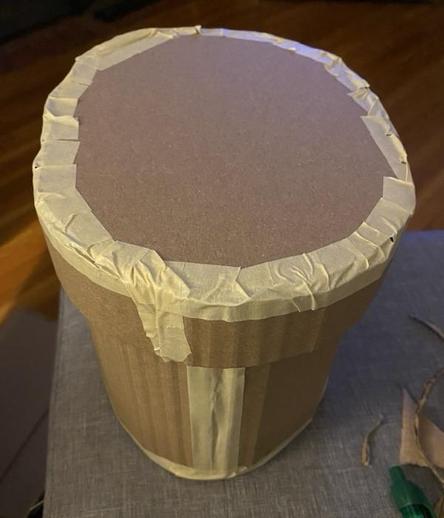 photo of a cylindrical, cardboard container with a taped, flat lid.