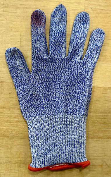 A cut-proof glove, with a blood stain soaked through on the tip of the index finger.