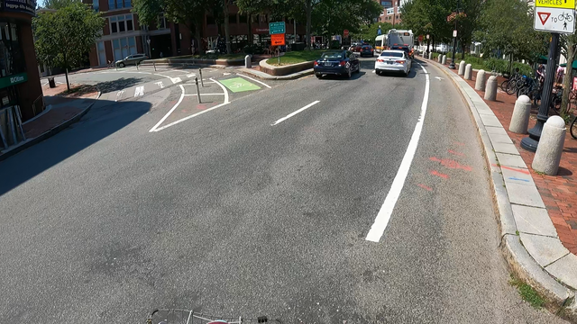 (Spoiler in the alt text after the description)

On Brattle Street, eastbound, just as it enters "Brattle Square" in Harvard Square, heading for Mt. Auburn eastbound (Brattle Square is the triangle where Mt. Auburn St runs along one edge, and Brattle St curves at the opposite point).  Full sunlight.

To my right I see the backside of two lanes of traffic lined up at the stop sign at Mt. Auburn Street.

The car in the left lane, a black Mercedes, has its backup lights illuminated, but it's…
