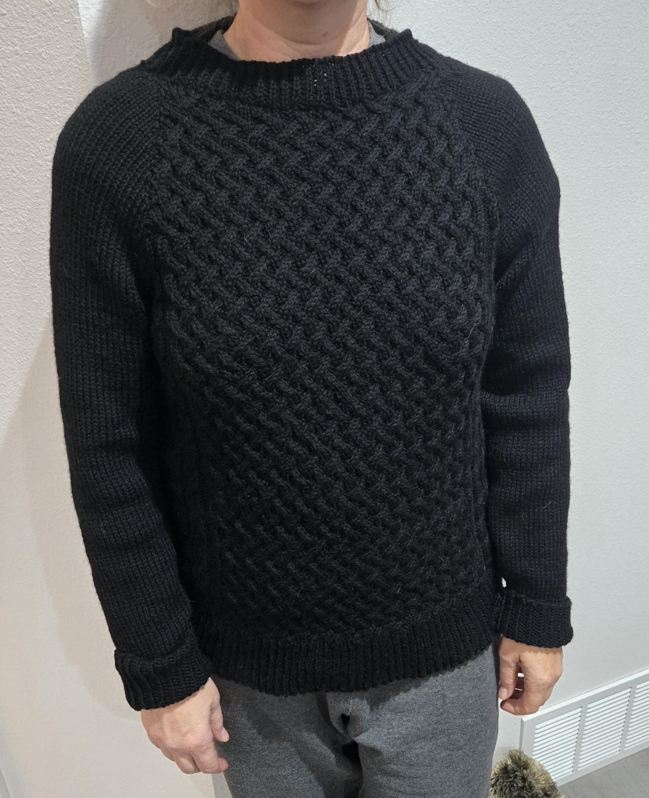 Black sweater with a basket weave cable on the front.