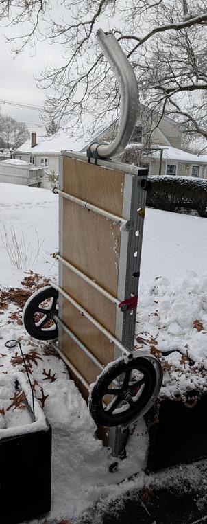 A bikes at work trailer, jammed vertically into a pile of snow between two large square planters.

The background is all snowy, the sky is overcast, it looks cold (it's actually about freezing).
