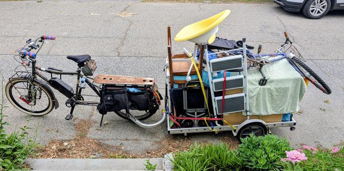 A trailer attached to a longtail bicycle with an after-market e-assist.  The trailer contains:

One ikea two-pedestal+drawers desk,
two mesh-drawer pedestal things,
a folding dolly,
a folding short step ladder,
a wooden chair,
a rolling chair,
a muddy shoe tray,
and a bicycle.
