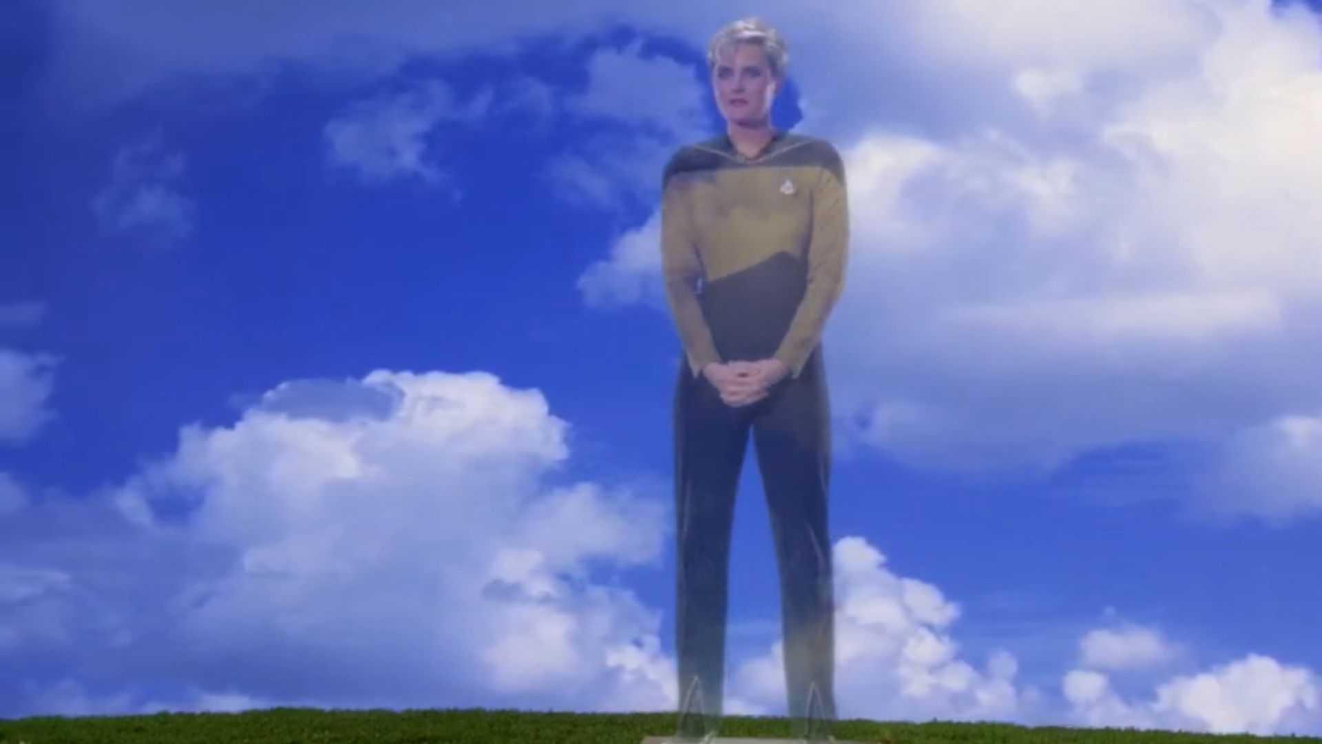 A woman in a gold and black uniform standing on a green hill with clouds in the background